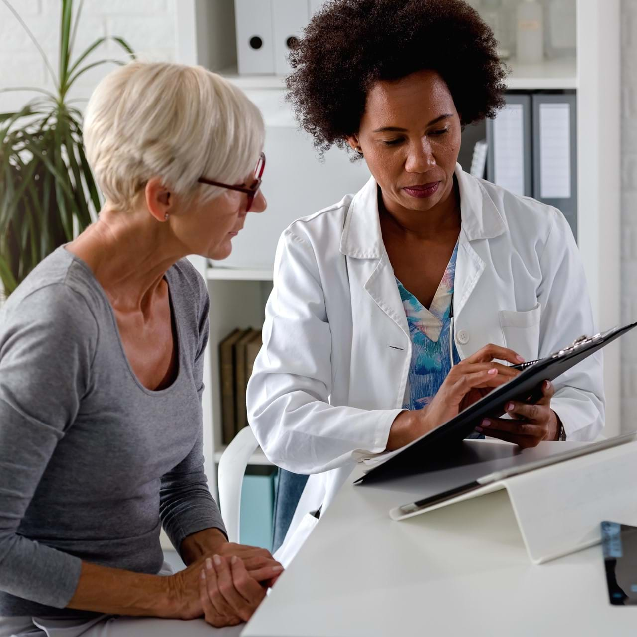 Doctor showing woman information on clipboard