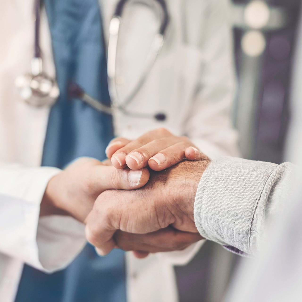 closeup of doctor grasping patient's hand