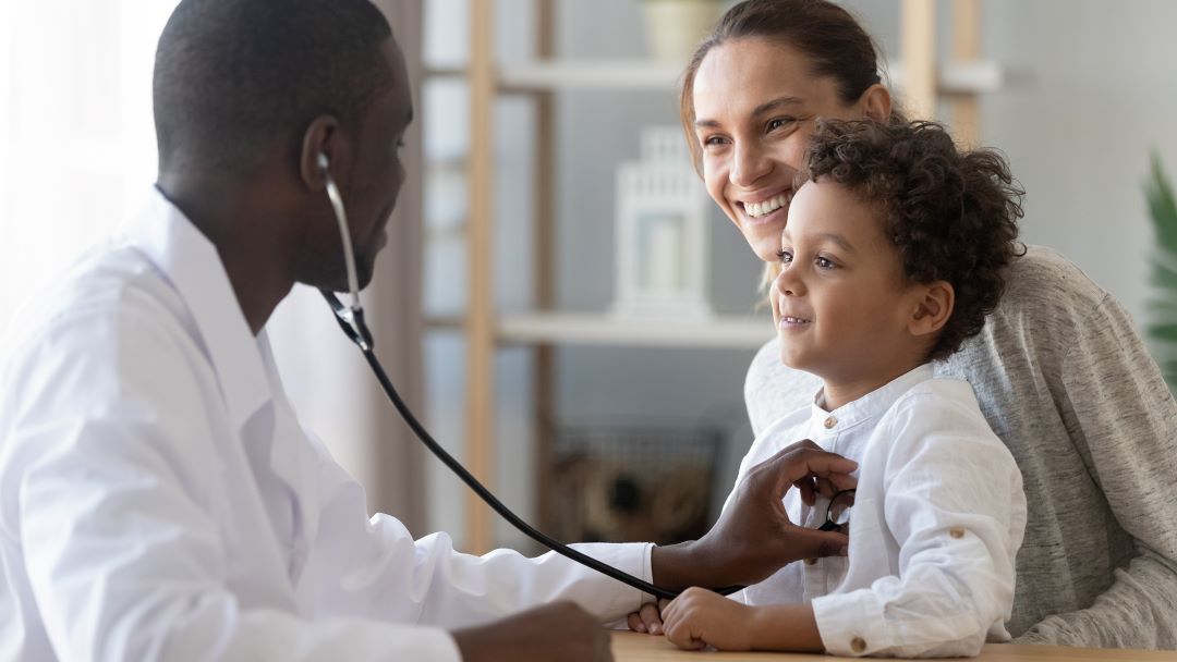 Doctor using stethescope with mother and child